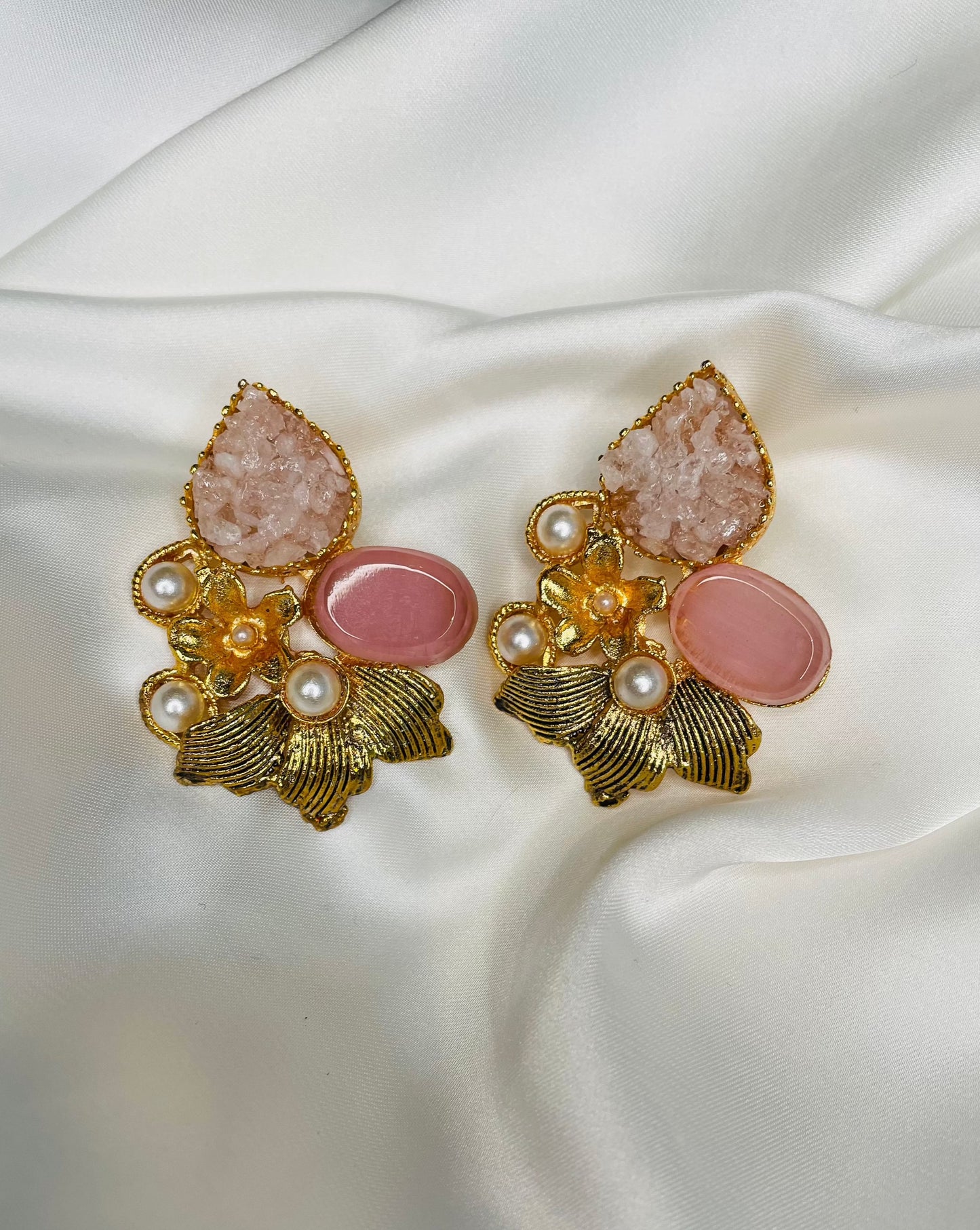 Heavy golden eastern statement earrings in leaf shape embellished with Blush Pink stone and White crushed stones along with pearls to compliment with your eastern look.